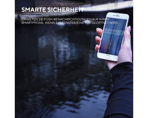 Person hält ein Smartphone mit einer Push-Benachrichtigung über ein geöffnetes Fenster oder eine Tür