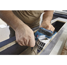 Handwerker hobelt Holz mit einem Elektrohobel der Marke Bosch