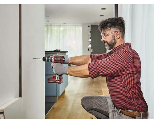 Ein Mann bohrt mit einer Bohrmaschine ein Loch in die Wand.