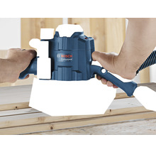 Eine Person verwendet eine Bosch GOF 1250 CE Oberfräse auf einem Holzbrett.