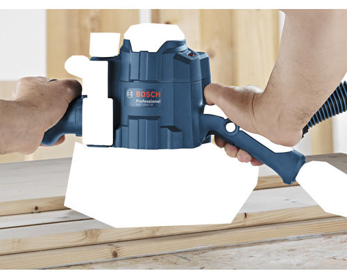 Eine Person verwendet eine Bosch GOF 1250 CE Oberfräse auf einem Holzbrett.