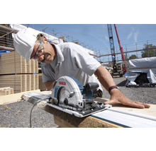 Ein Mann schneidet Holz mit einer Bosch Handkreissäge auf einer Baustelle.