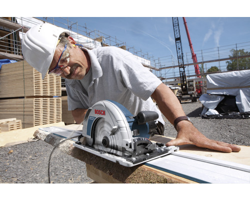 Ein Mann schneidet Holz mit einer Bosch Handkreissäge auf einer Baustelle.