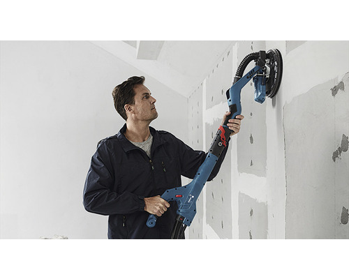 Mann schleift Wand mit einem Trockenbauschleifer