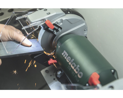 Mann schleift Metall mit einem Metabo Doppelschleifer, Funken fliegen.