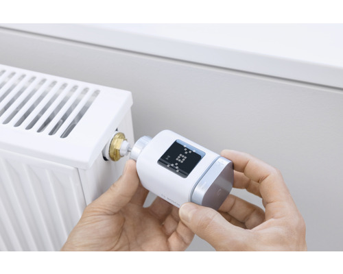 Person montiert elektronischen Heizkörperthermostat an einem Heizkörper
