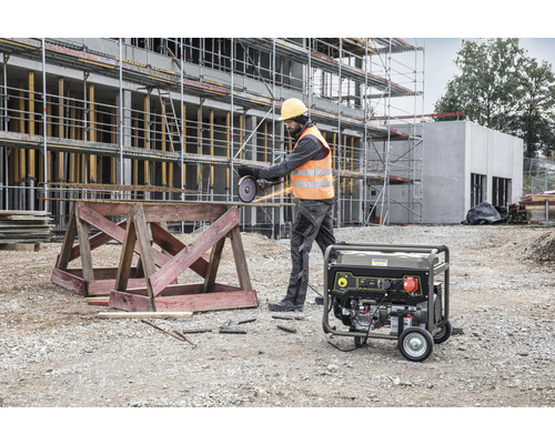 Mann schneidet Armierungseisen mit einem Trennschleifer auf einer Baustelle. Im Hintergrund ist ein Stromgenerator zu sehen.
