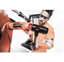 Ein Mann mit Schutzbrille verwendet einen Hammer, um eine Maschine zu reparieren.