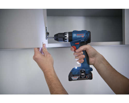 Akku-Bohrschrauber beim Anbringen eines Scharniers an einer Schranktür
