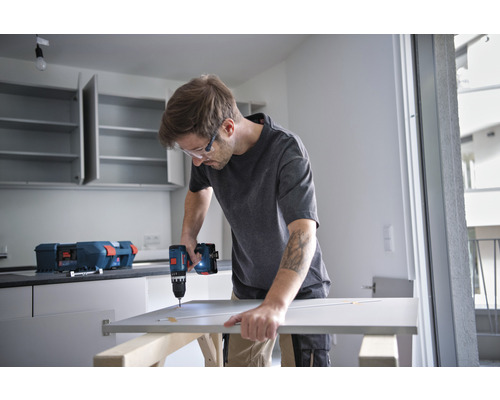 Mann montiert eine Küchentür mit einem Akku-Bohrschrauber