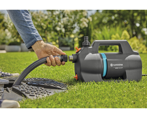 Gartenbewässerungsszene mit einer Person, die einen Schlauch an eine Gardena Gartenpumpe anschließt