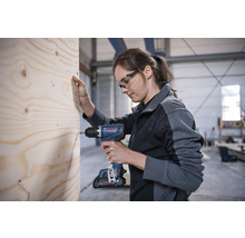 Frau schraubt Schraube mit Akku-Bohrschrauber in Holz