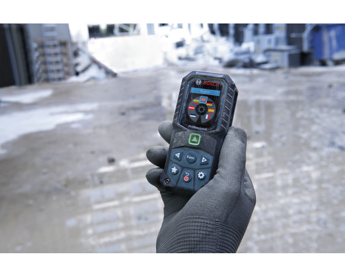Eine Hand mit Handschuh hält ein digitales Entfernungsmessgerät von Bosch.