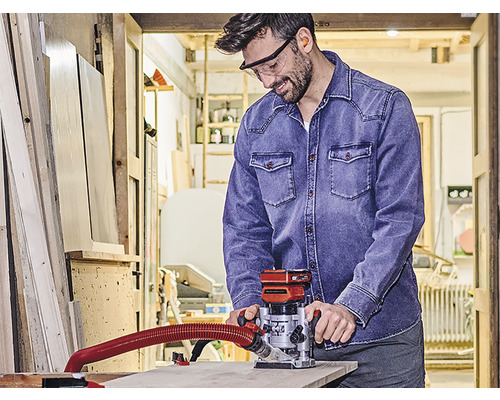 Ein Mann in einer Werkstatt benutzt eine Oberfräse für Holzarbeiten.