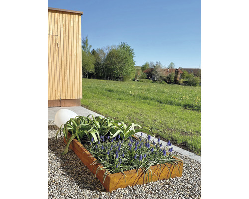 Blumenkasten aus Metall mit blühenden Pflanzen und einer dekorativen Kugel im Garten