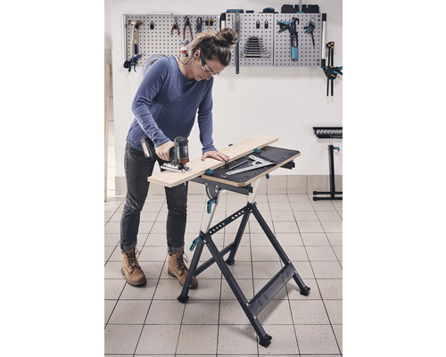 Frau arbeitet mit Stichsäge an einer Werkbank in einer Werkstatt.