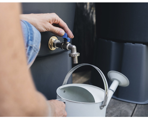 Eine Person befüllt eine Gießkanne mit Wasser aus einem Regenspeicher.