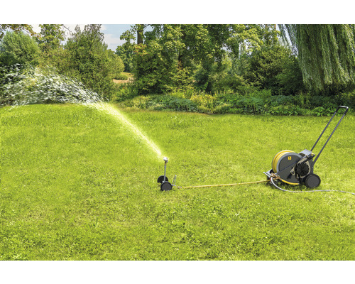 Gartenszene mit Rasensprenger und Schlauchwagen in Betrieb