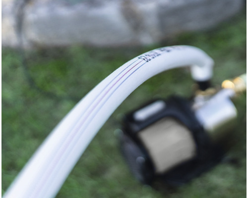 Weißer Wasserschlauch verbunden mit einer Pumpe für den Garteneinsatz