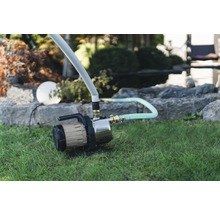 Garten mit Gartenpumpe und Bewässerungsschlauch auf dem Rasen