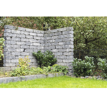Graue Gartenmauer mit Bepflanzung im Garten