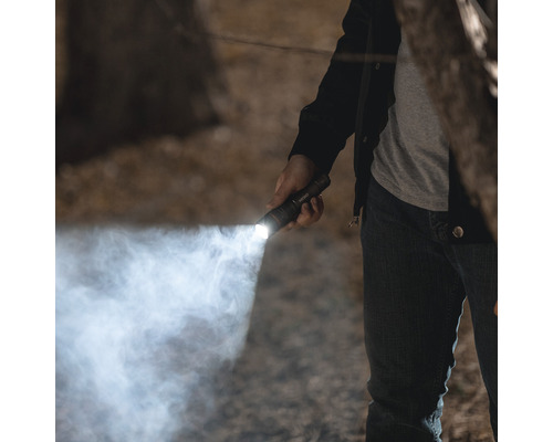 Eine Person leuchtet mit einer Taschenlampe in der Dunkelheit.