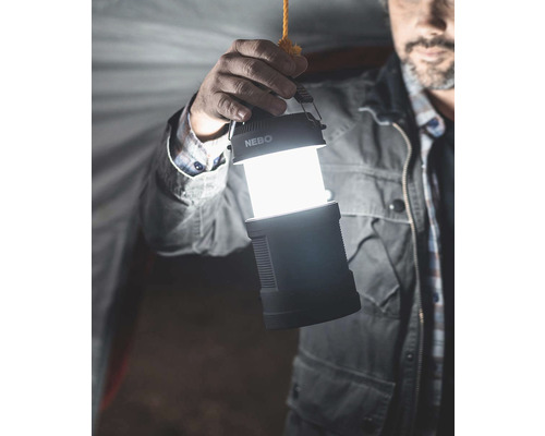 Eine Person hält eine leuchtende Campinglaterne der Marke Nebo.