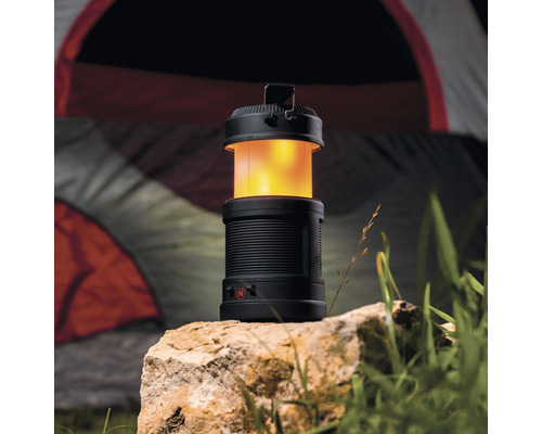 Schwarze Campinglampe auf einem Stein vor einem Zelt