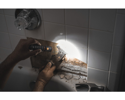 Szene im Badezimmer mit einer Person, die Fliesen repariert und eine Taschenlampe zur Beleuchtung verwendet