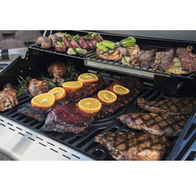 Grill mit verschiedenen Speisen wie Rippchen, Steak und Gemüse.