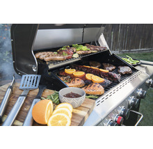 Grill mit Fleisch, Gemüse und Grillzubehör auf einem Holztisch
