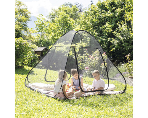 Kinder spielen in einem Insektenschutzzelt im Garten.