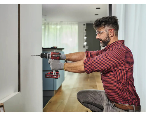 Mann bohrt mit einem Akku-Bohrschrauber ein Loch in eine Wand.