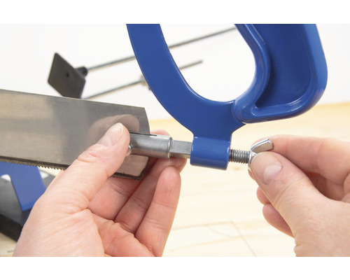 Detailaufnahme einer Metallsäge, die von einer Hand fixiert wird