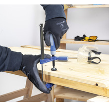 Eine Person befestigt eine Werkstück mit einer Einhandzwinge auf einer Holzoberfläche.