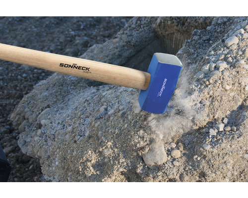 Schwerer Hammer aus Stahl mit Holzgriff beim Zerkleinern von Steinen