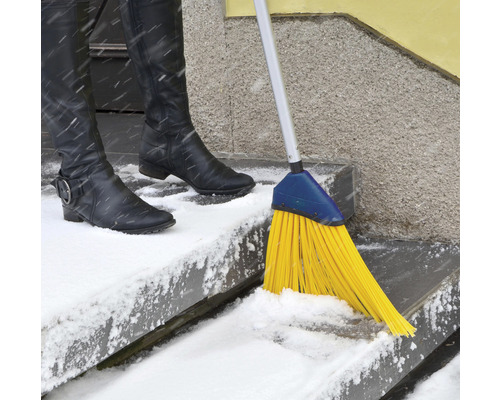 Szene mit einer Person, die mit einem Besen Schnee von einer Treppe fegt