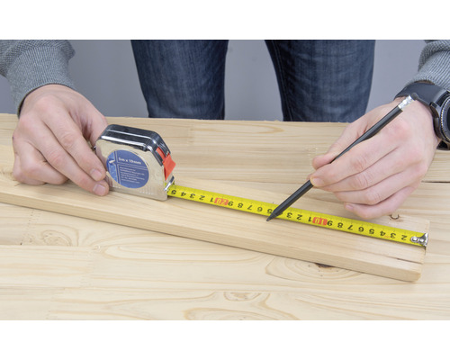 Zollstock und Bleistift zum Messen eines Holzbretts