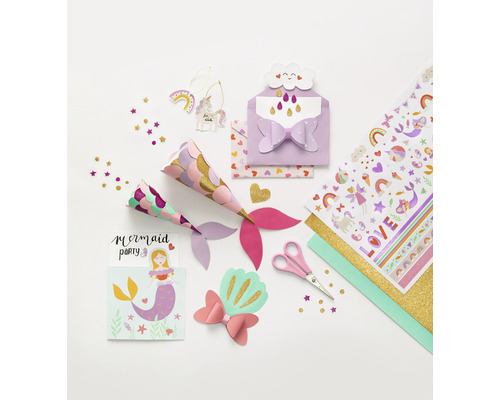 Verschiedene Bastelmaterialien für eine Meerjungfrauenparty liegen auf einem Tisch, darunter Partyhüte, Einladungen, Aufkleber, Scheren und Konfetti.