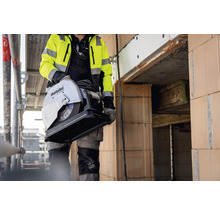 Ein Bauarbeiter trägt eine Metabo CS 23-355 S Metalltrennsäge auf einer Baustelle.