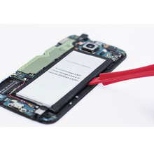 Geöffnetes Smartphone mit herausgenommener Batterie und rotem Werkzeug