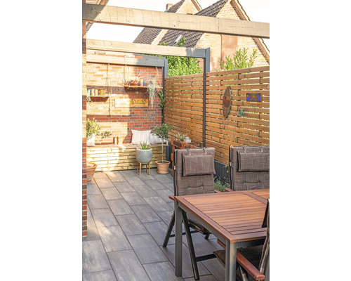 Terrasse mit Sitzbereich, Holzzaun und Pflastersteinen