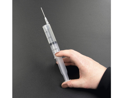 Eine Hand hält eine 20 Milliliter Spritze mit Nadel.