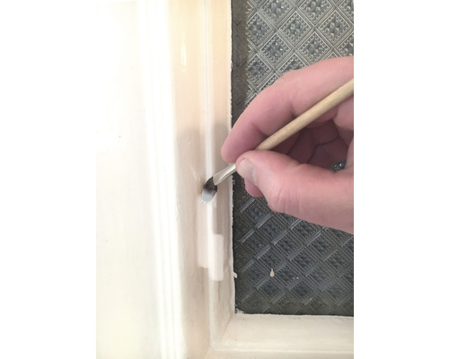 Ein Pinsel wird verwendet, um Farbe auf einen Fensterrahmen aufzutragen.