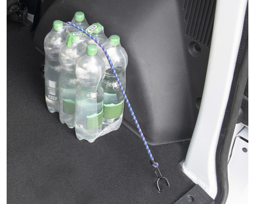Eine Packung Mineralwasser ist mit einem Spanngurt im Kofferraum eines Autos gesichert.