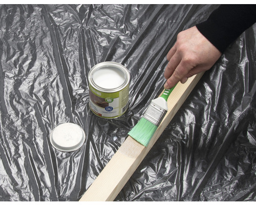 Anstreichen eines Holzstücks mit einem Pinsel und einer Dose Holzgrundierung.
