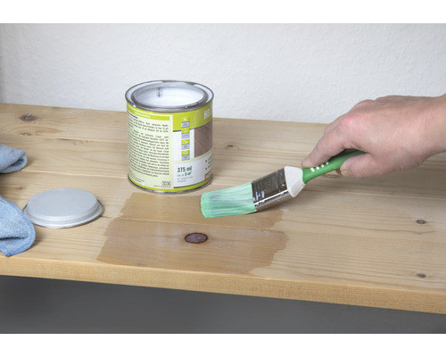 Holzlasur Dose mit Pinsel beim Auftragen auf ein Holzbrett