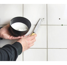 Fliesenreparatur mit Spachtel und Füllmaterial