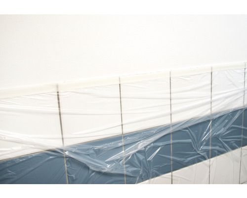 Abgedeckte Fliesenwand im Badezimmer zum Schutz vor Schmutz und Beschädigungen während Renovierungsarbeiten.