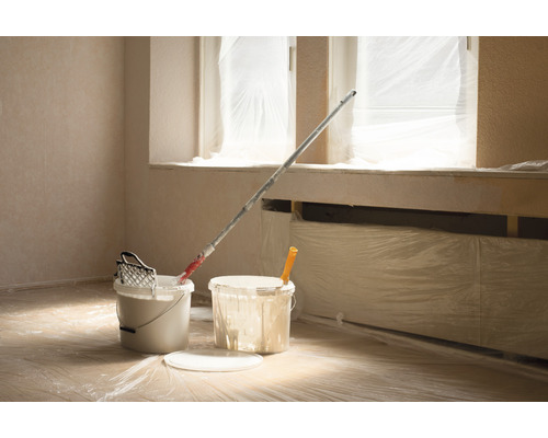 Zimmer mit Malereibedarf wie Eimer, Farbroller und Abdeckfolie
